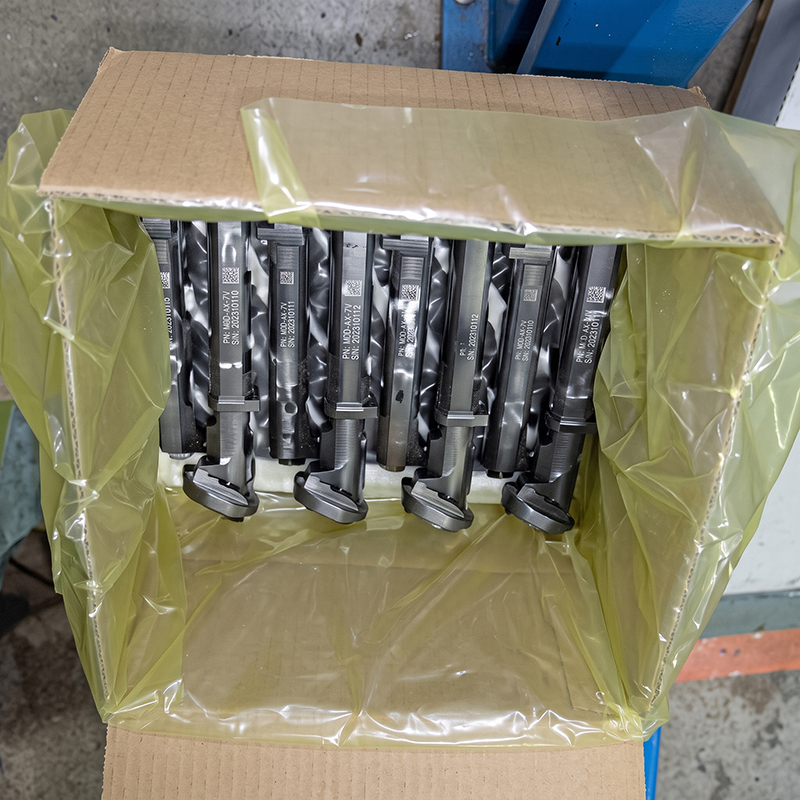 紙箱內以黃色防鏽袋包覆並整齊排列的金屬零件